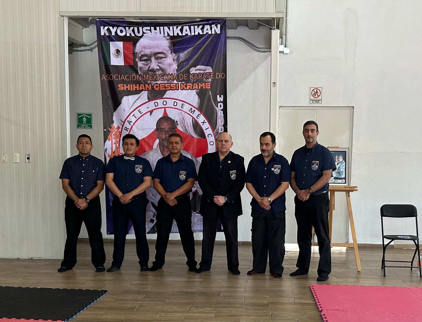 Oficiales del evento frente al banner de la Asociación Mexicana de Karate Do